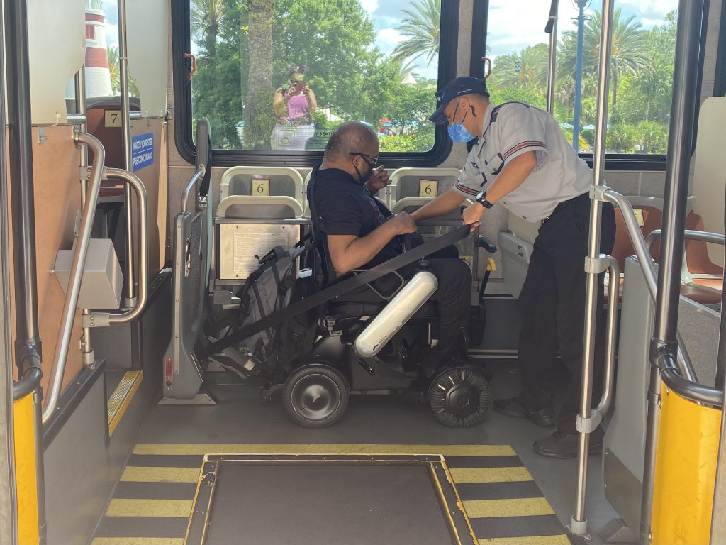 Man in wheelchair is buckled into harnesses on a passenger bus