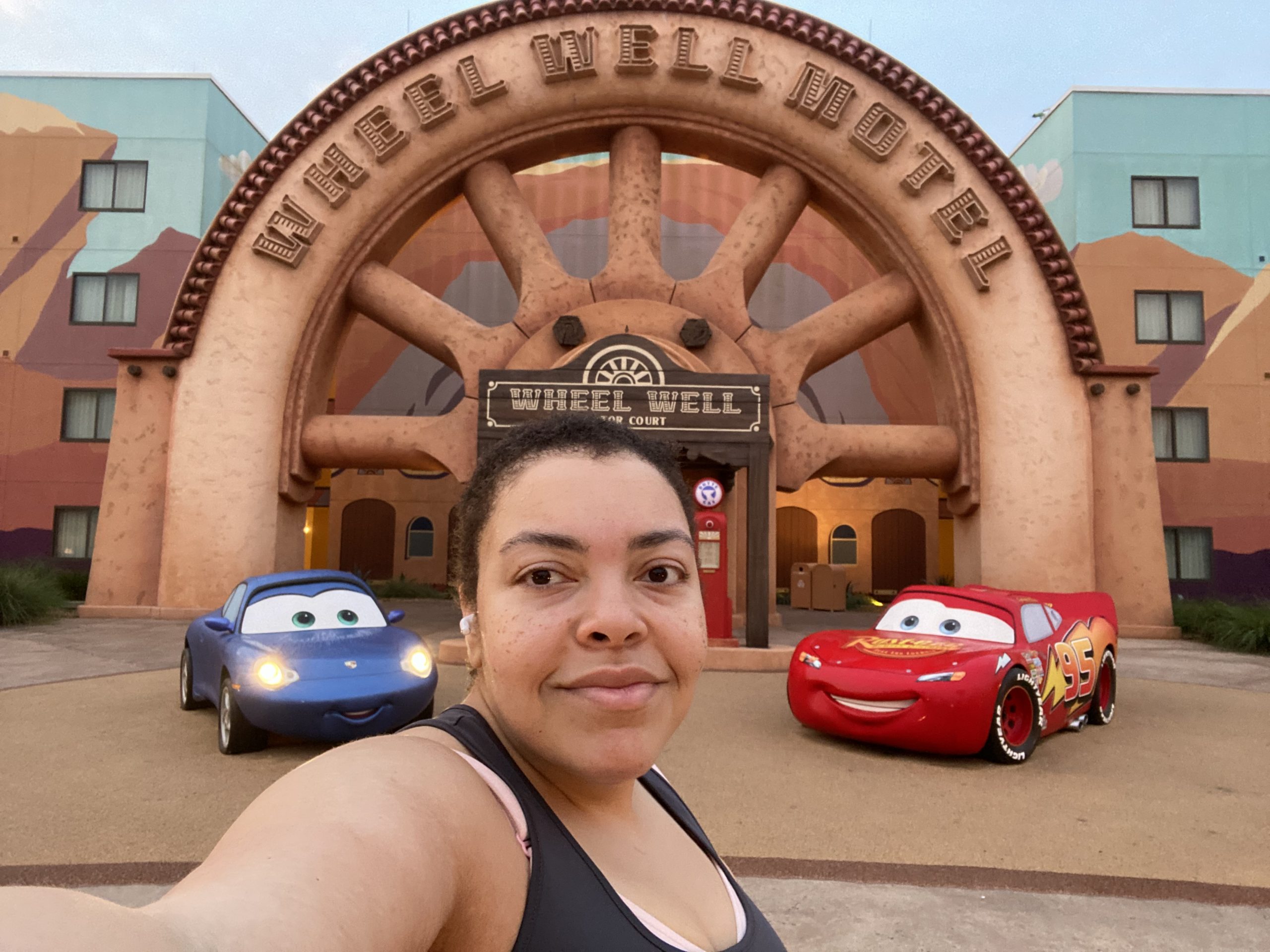Woman poses in front of statues from the Pixar movie Cars